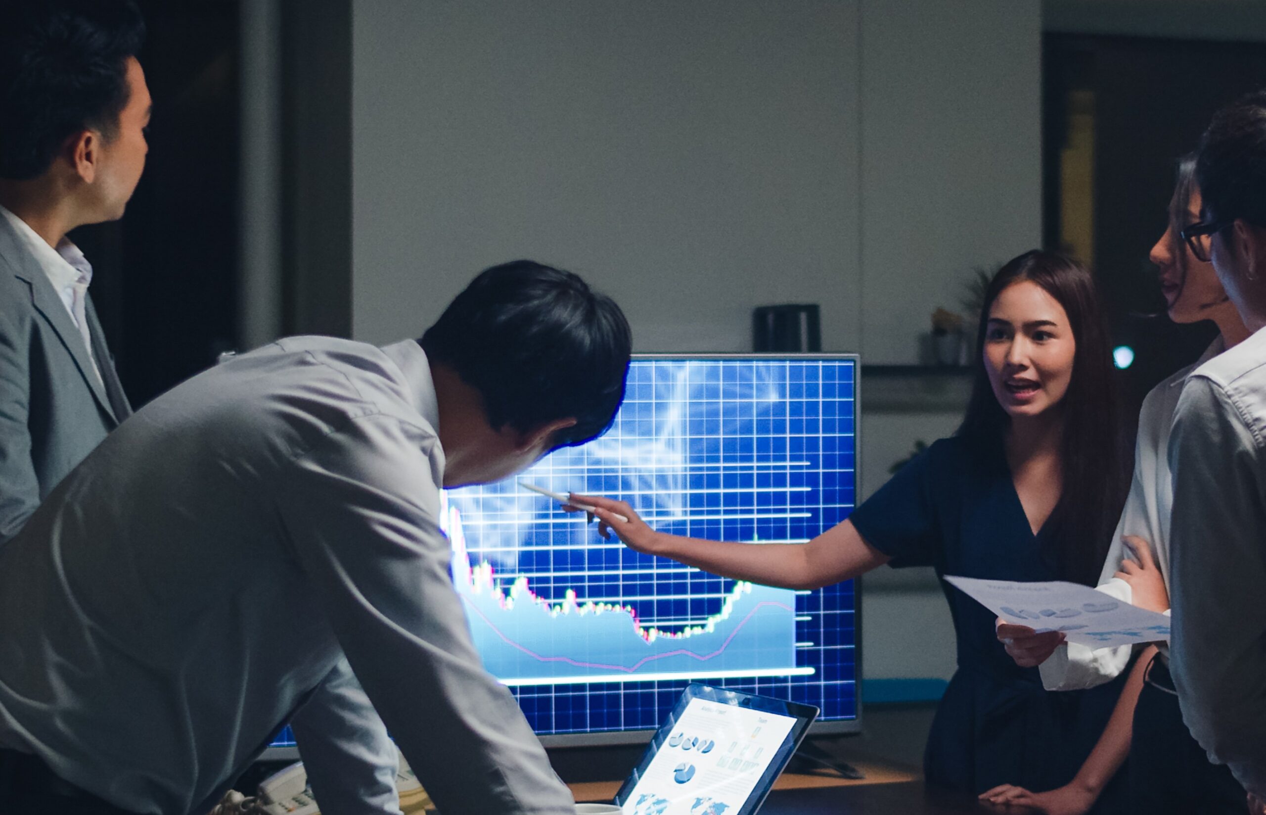 Asia businessmen and businesswomen meeting brainstorming ideas conducting business presentation project colleagues working together plan success strategy enjoy teamwork in small modern night office.